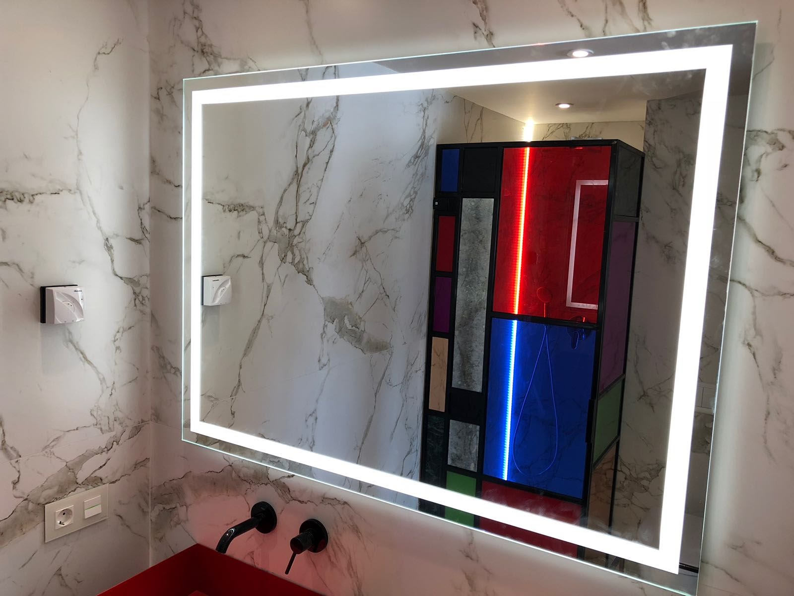 Espejo a medida retroiluminado sobre pared de mármol